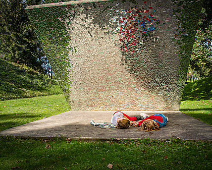 Zwei Kinder beim spielerischen Entdecken von Gustav Trogers Skulptur "Materialprobe: Sieg über die Sonne, Kunst sich über die Natur lustig zu machen" 2004.