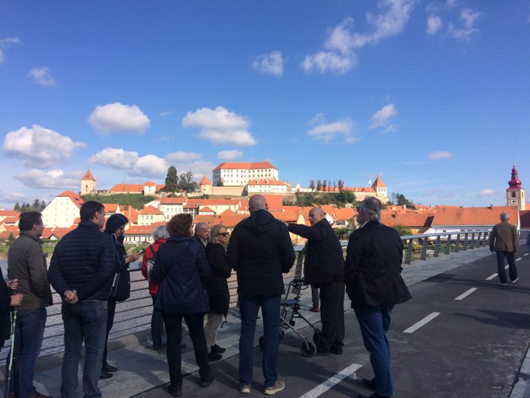 Gruppe von Menschen auf der Straße blickt auf eine von der Sohne bestrahlte Stadt.