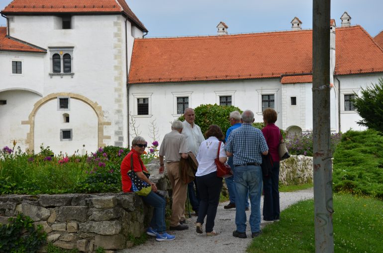 Leopold Toifl steht mit einer Gruppe von Menschen im Rahmen einer Führung vor einem Gebäude mit rotem Dach in Varzdin (Kroatien).