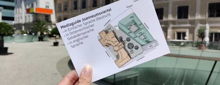 Foto der Vorderseite einer Infokarte zum neuen Mediaguide mit einer Abbildung des Joanneumsviertels von oben