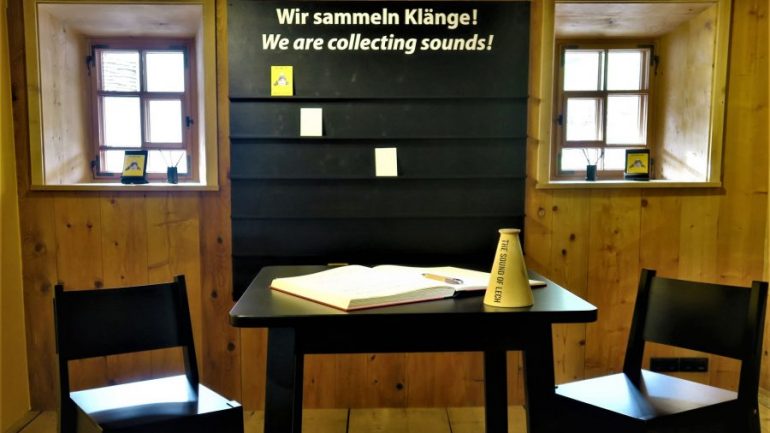 Ausstellungsraum mit einem Tisch und zwei Stühlen zum Thema "Wir sammeln Klänge"