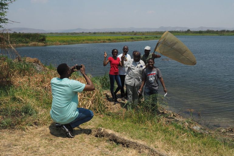 Workshop-Teilnehmende mit Insektenfangnetz am Ufer des Flusses Kafue in Sambia.