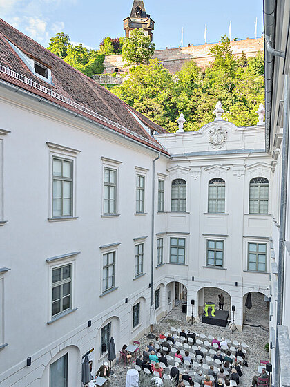 An event is held in the inner courtyard of the History Museum. There are chairs as well as standing tables.
