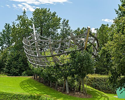 Im Berggarten entsteht in diesem Moment eine Arche aus lebenden Bäumen. Das 25m lange Holzgerüst dient seit mehr als einem Jahrzehnt als temporäre Stütze für den Pflanzenwuchs. 