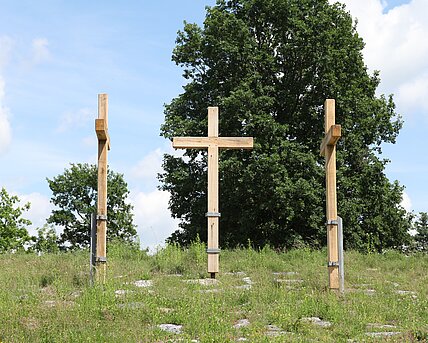 Drei große Kreuze stehen im Berggarten des Skulpturenparks. Die Möglichkeit einen Nagel einzuschlagen, macht das Kunstwerk interaktiv. 