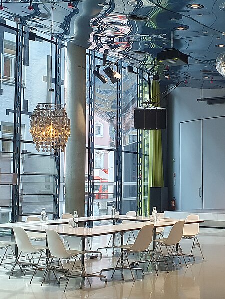 In Space04 there is a meeting table with armchairs under a silver ceiling light. In the background is the podium.