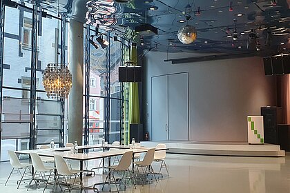 In Space04 there is a meeting table with armchairs under a silver ceiling light. In the background is the podium.