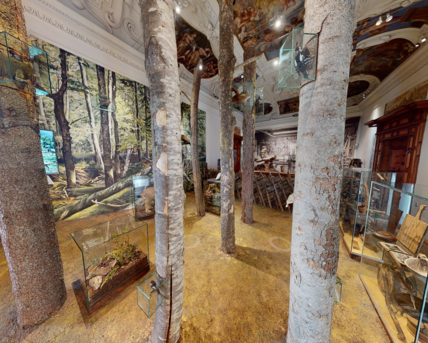 Screenshot von einem 360 Grad Rundgang. Zu sehen ist der Ausstellungsraum "Von Wald und Holz" mit Baumstämmen in der Mitte des Raumes.