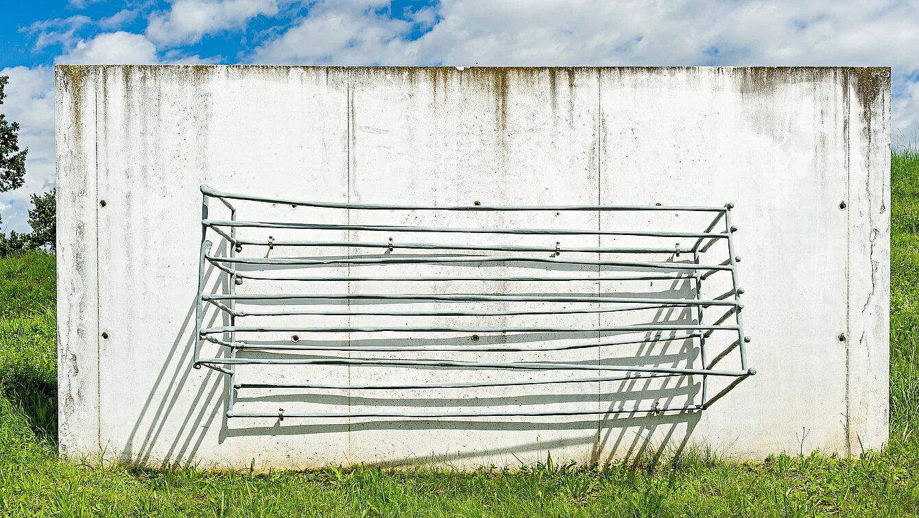 A vertical concrete slab with metal rods that form a basket.