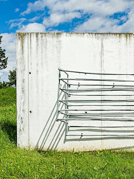 A vertical concrete slab with metal rods that form a basket.