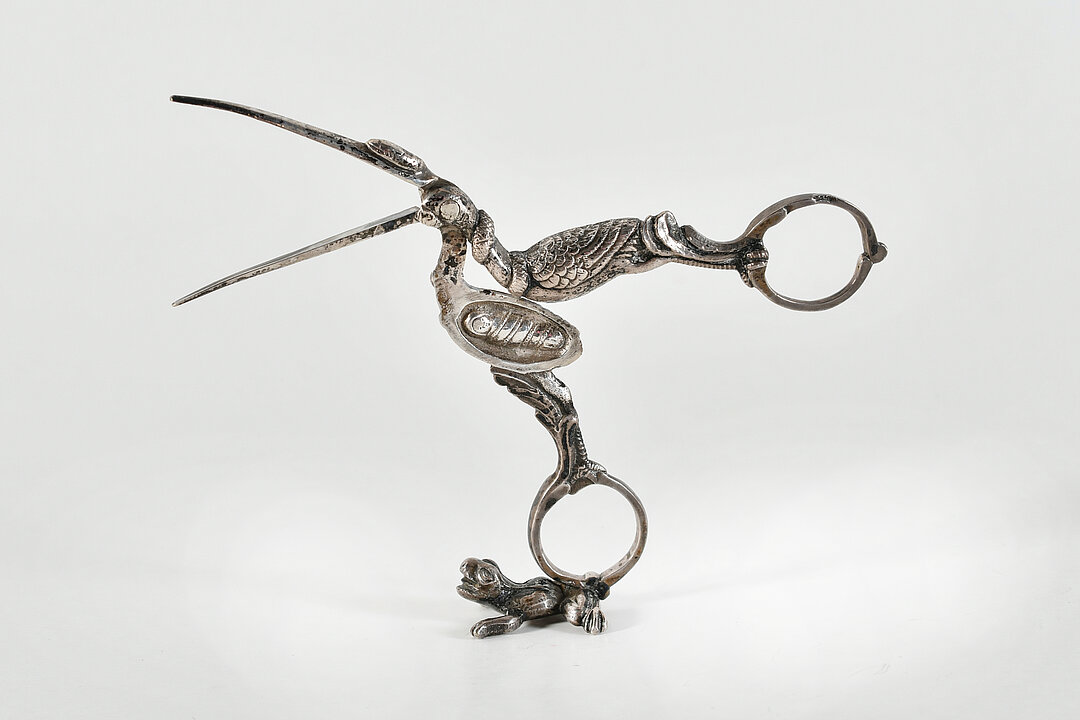Eine Schere aus silbernem Metall in Form eines Storchs