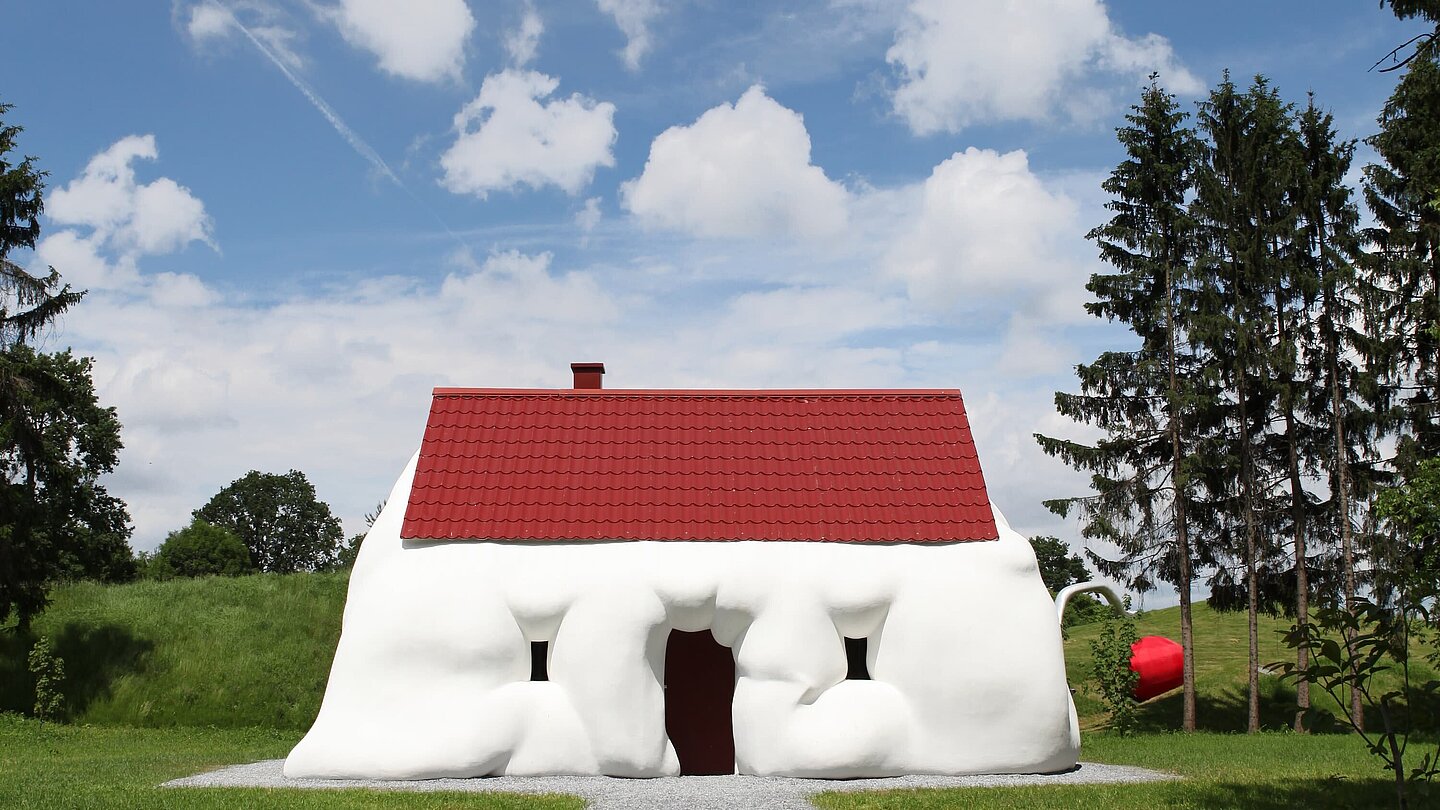 Ein aufgequollenes Einfamilienhaus thematisiert Reichtum und Konsum. 