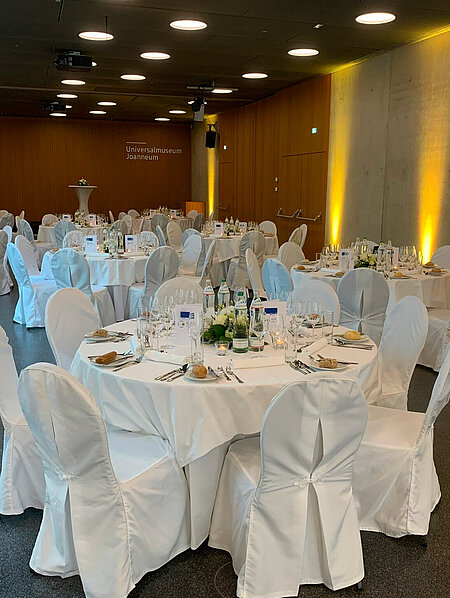 Runde Galatische im Auditorium im Joanneumsviertel, gedeckt und mit Blumenschmuck. 