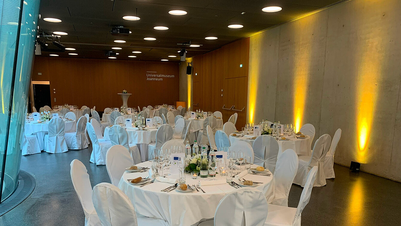 Runde Galatische im Auditorium im Joanneumsviertel, gedeckt und mit Blumenschmuck. 