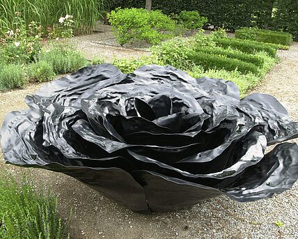 Die Skulptur aus Aluminium stellt ein überdimensionales Rosenblatt dar. 
Die Skulpturen sind in vier unterschiedlichen Farben an öffentlichen Orten, in Parks und Gärten platziert. Die hier im Bauerngarten befindliche schwarze Rose entfaltet ihre Wirkung im Wechselspiel mit der sie umgebenden Natur.