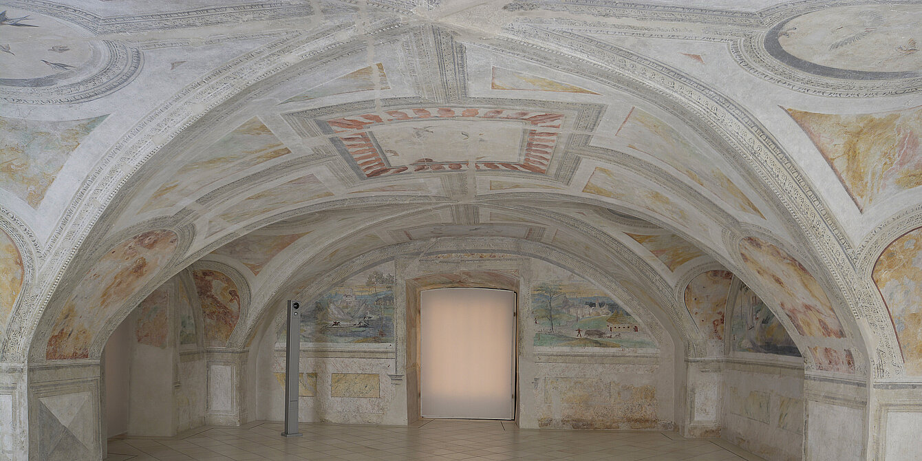 Fotografie von einem Raum mit gewölbter Decke. An der Decke sind Fresken in hellen Farben gemalt.