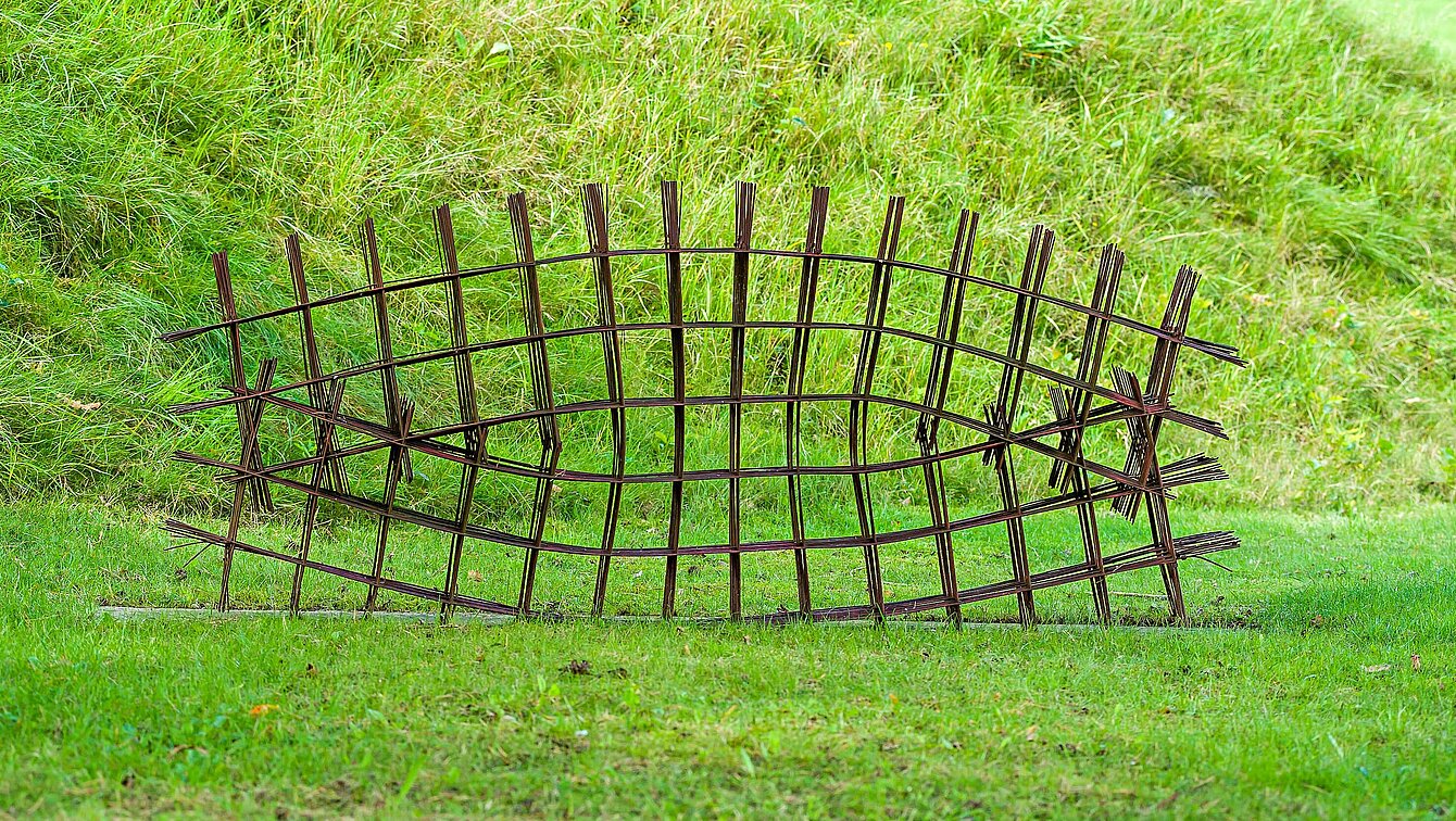 Oxidized structural steel lattice whose struts are interwoven like branches or wood to form a regular "grid".