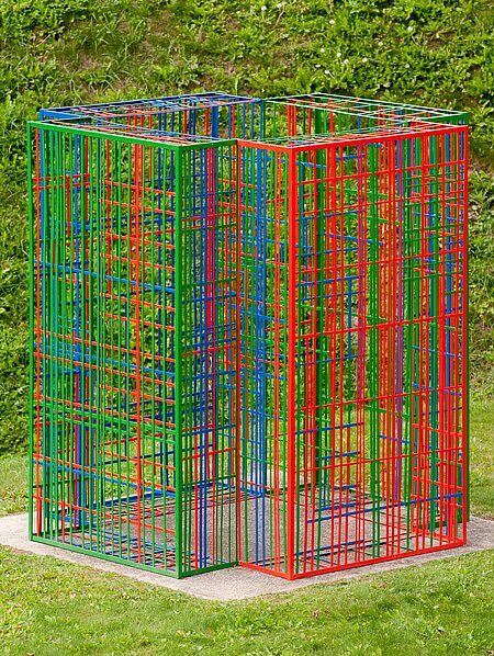 Die Skulptur besteht aus farbigen Metallstreben steht auf einem Sockel. Vier farbigen Module aus Metall überlagern und vernetzen sich je nach Blickwinkel immer anders.