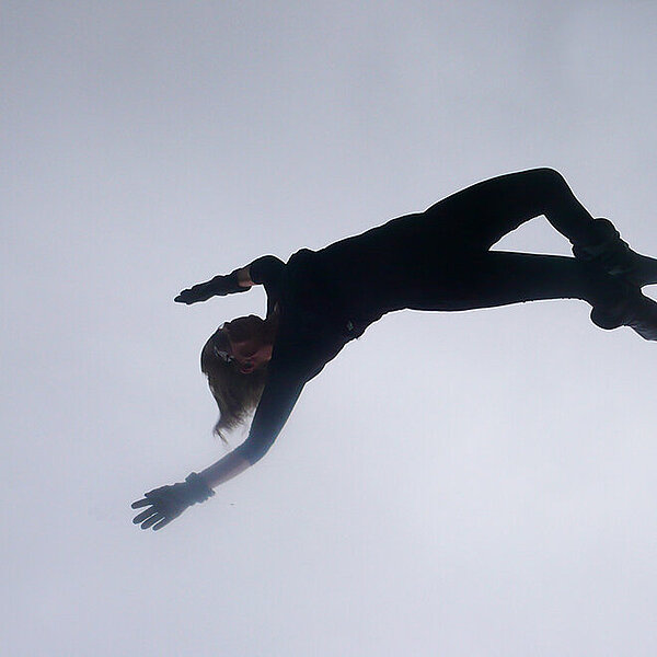 The silhouette of a woman, depicted in landscape orientation, appears to be floating or falling through the gray sky.