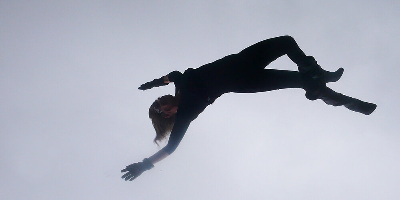 The silhouette of a woman, depicted in landscape orientation, appears to be floating or falling through the gray sky.