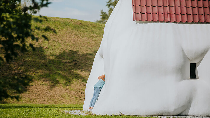 Ein Kind erkundet die Skulptur "Fat House" von Erwin Wurm.