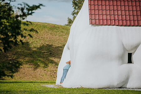 Ein Kind erkundet die Skulptur "Fat House" von Erwin Wurm.