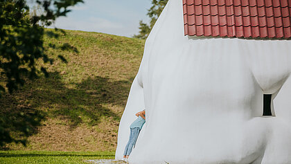 Ein Kind erkundet die Skulptur "Fat House" von Erwin Wurm.