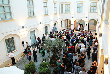 People stand in the inner courtyard of the History Museum and look towards the stage.