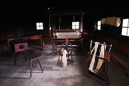 Geräte zur Verarbeitung von Flachs und zur Erzeugung von Stoff im Inneren der Brechelhütte.