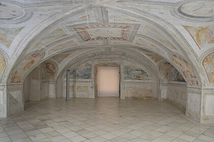 Fotografie von einem Raum mit gewölbter Decke. An der Decke sind Fresken in hellen Farben gemalt.