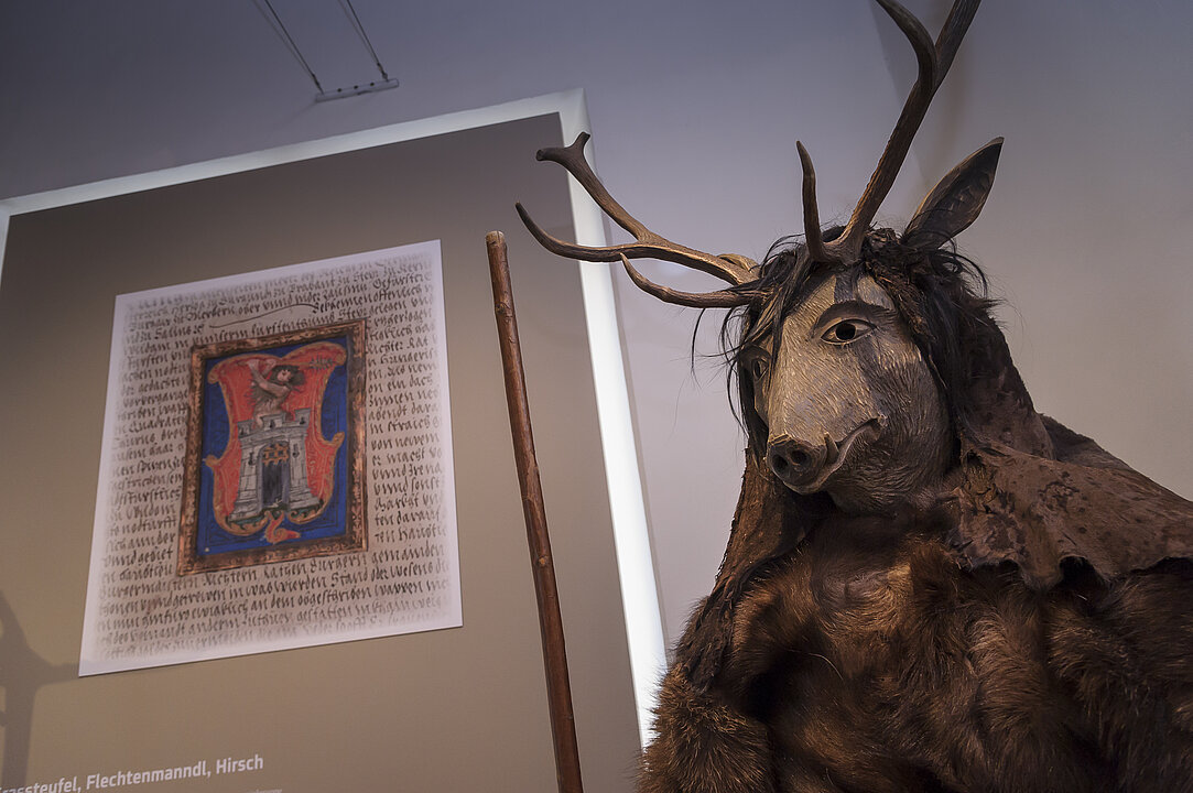 Foto von einer lebensgroßen Figur mit Hirschgeweih, Tiergesicht und Fellen.