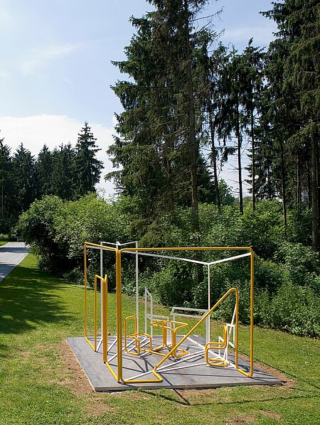 Ein Raum aus runden Metallrohren, in dem Wände und Gegenstände nur Umrissen sind. Die Schattenlinien werden durch eckige Stahlrohre ergänzt. Uncinis Werk steht im Berggarten des Skulpturenparks. 