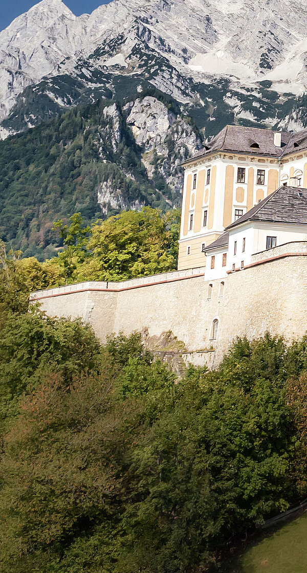 Ansicht auf Schloss Trautenfels bei blauem Himmel, im Hintergrund ist ein Berg zu sehen.