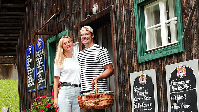 Besucherin und Besucher mit Picknickskorb vor der Jausenstation.
