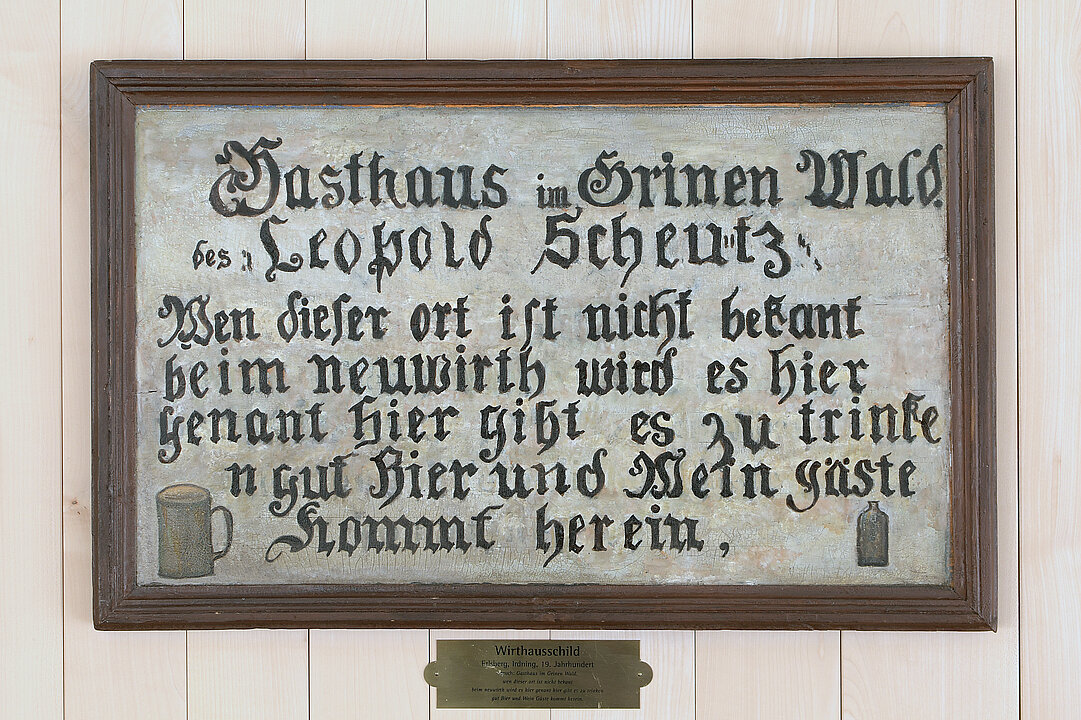 White inn sign with the old german inscription: "Gasthaus im Grinen Wald des Leopold Scheutz. Web dieser ort ist nicht bekant beim neuwirth wird es hier genant hier gibt es zu trinken gut Bier und Wein Gäste kommt herein" (The pub in the Green Forest of Leopold Scheutz. Who this place is unknown to, it is called Neuwirth. Here you can drink good beer and wine. Guests come in)