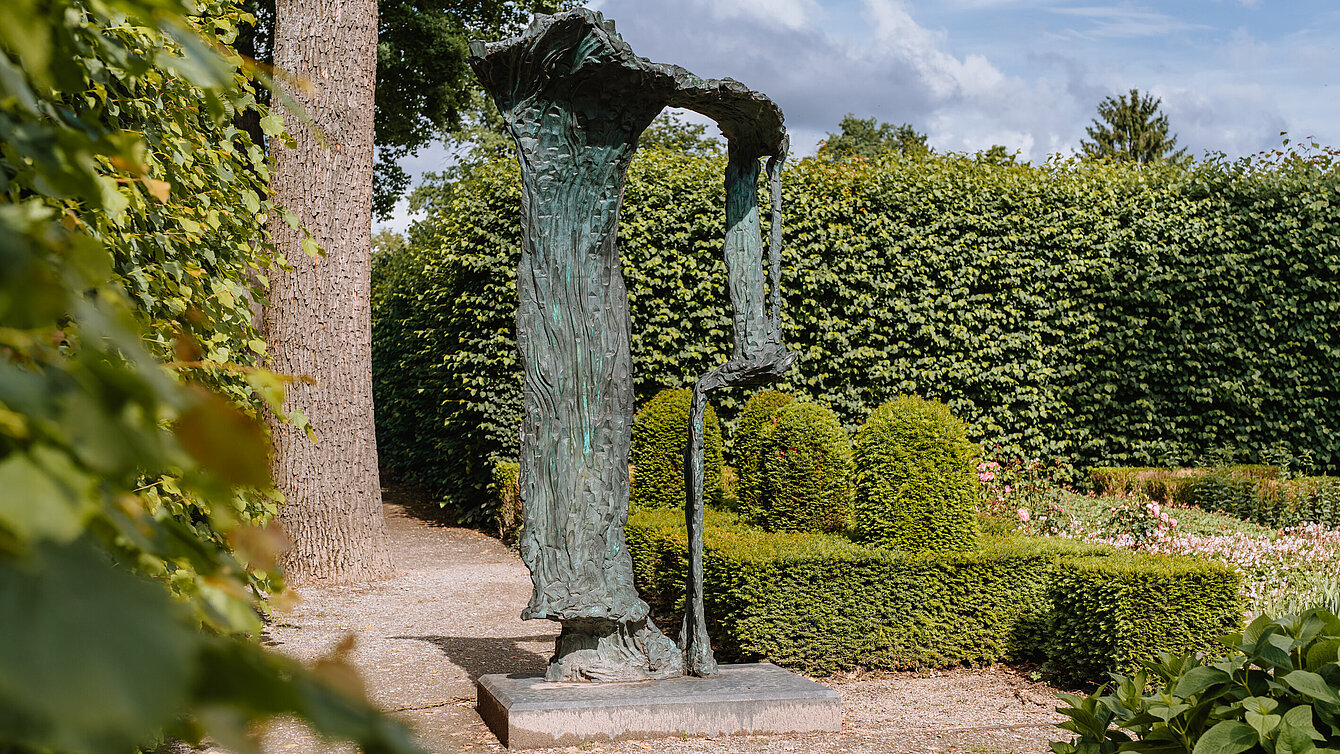 Bronzeskulptur auf Betonsockel, die einen erstarrten Wasserfall eindrucksvoll nachbildet.