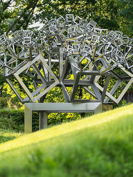 The sculpture is an ingenious construction in which five further cubes grow from one cube. The seemingly technical title refers to the year of creation, the shape (hexahedron) and the design. The cubes are reduced in size by a factor of 0.44902, and the proportions follow the golden ratio, creating a particularly harmonious effect. 