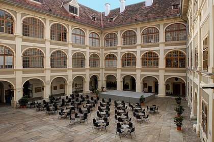 Im Lesliehof im Joanneumsviertel ist eine große graue Bühne sowie eine Kaffeehausbestuhlung aufgebaut.