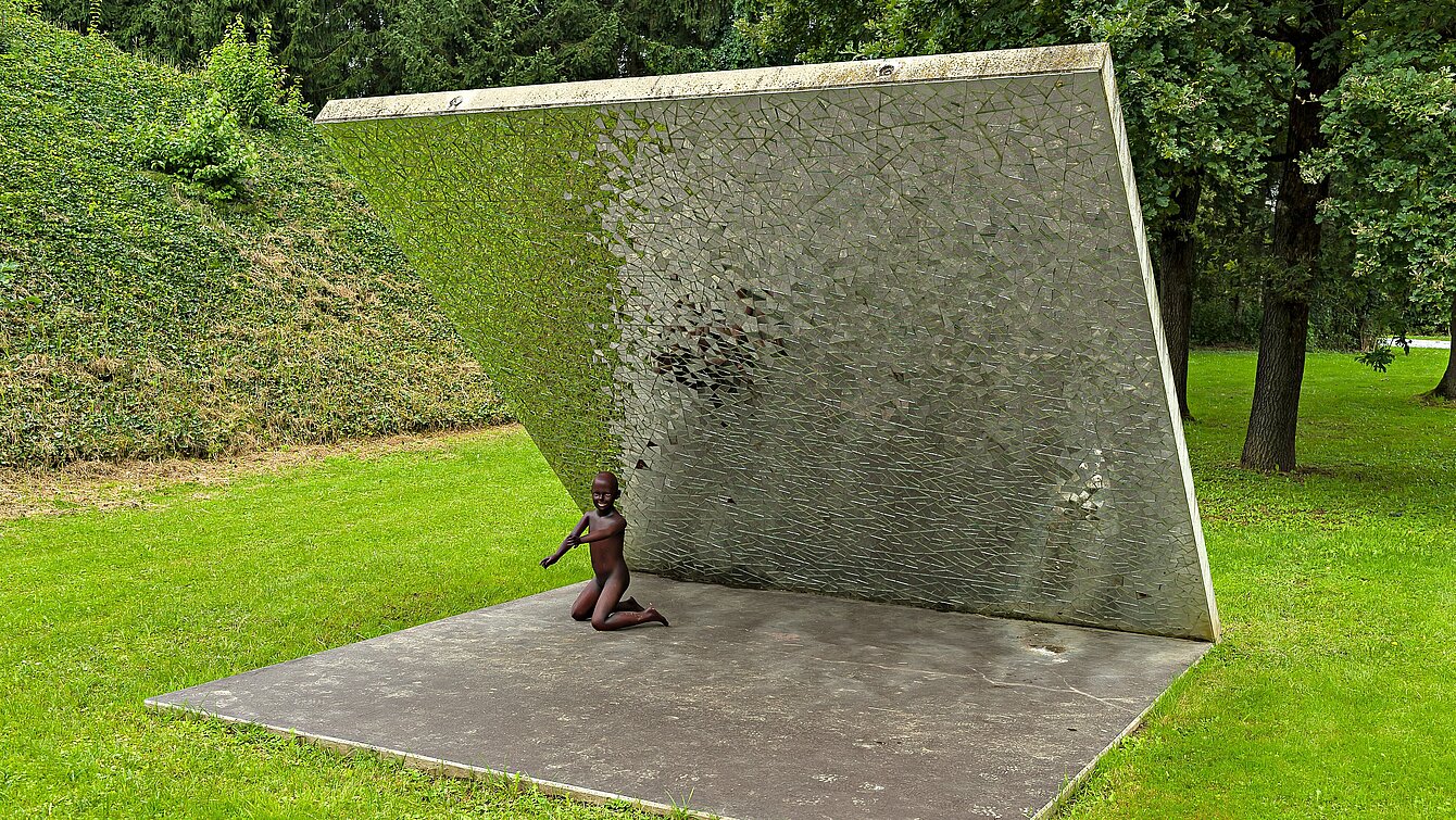 In the alpine garden of the sculpture park there is a diagonally rising concrete wall. It has small pieces of mirror on the underside. The environment is refracted by the sunlight in the shards. 