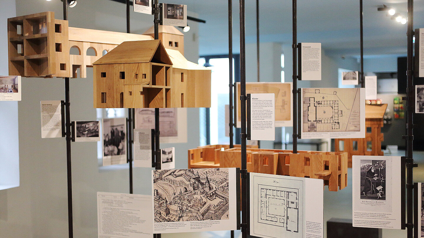 Dekoratives Ausstellungselement zur Geschichte des Volkskundemuseums am Paulustor mit alten Gebäudeplänen und Miniaturmodellen aus Holz.