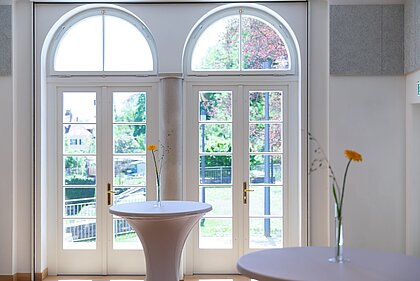 View through the double doors from the foyer into the fragrance garden. In the foyer are high tables with floral decorations.