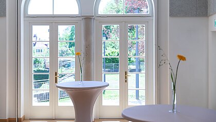 View through the double doors from the foyer into the fragrance garden. In the foyer are high tables with floral decorations.