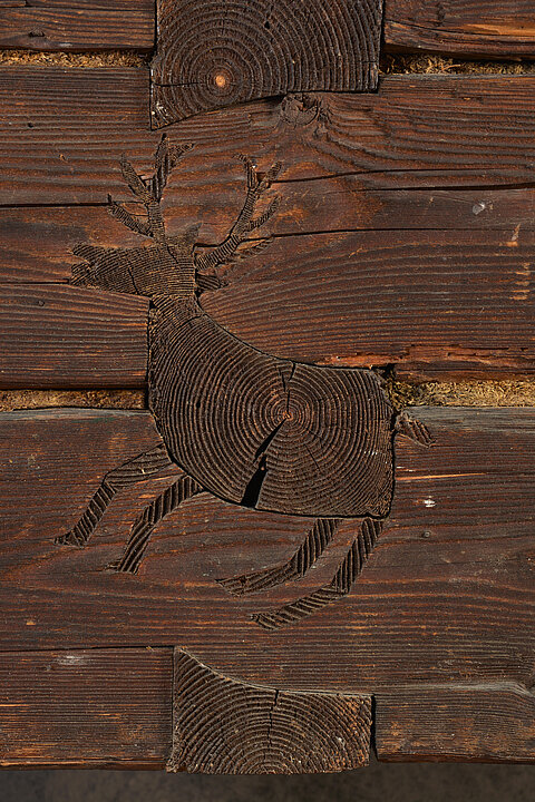 Another trunk in the shape of a deer is embedded in the trunks of a wooden wall.