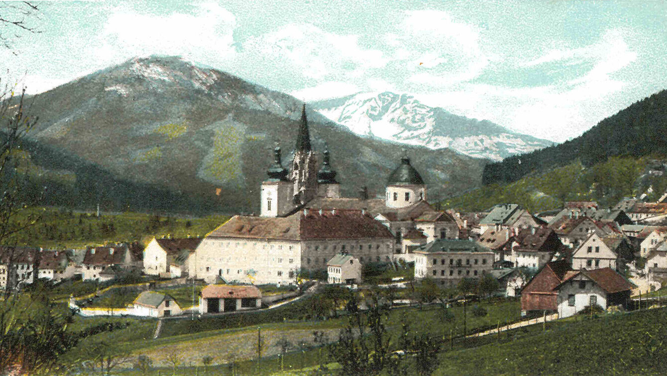 Postkartenansicht von Mariazell mit Basilika, im Hintergrund Berge.