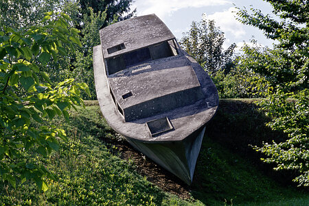 A concrete sculpture in the shape of a real boat appears to float on the hilly landscape o f the sculpture park.