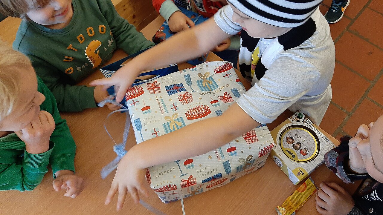 Kind freudig beim Geschenk auspacken