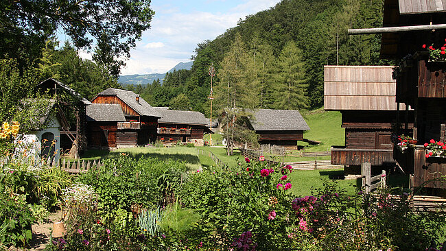 Frühling im Österreichischen Freilichtmuseum Stübing: Im Vordergrund ist ein Bauerngarten, im Hintergrund typisch steirische Gebäude zu sehen.