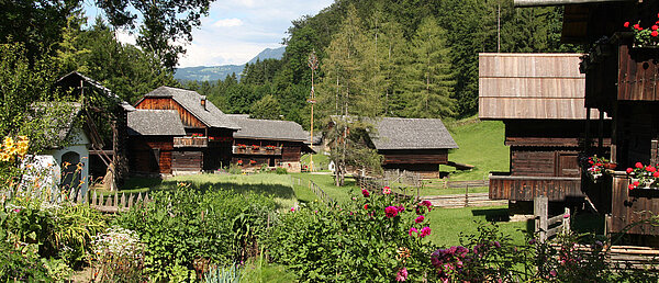 Frühling im Österreichischen Freilichtmuseum Stübing: Im Vordergrund ist ein Bauerngarten, im Hintergrund typisch steirische Gebäude zu sehen.