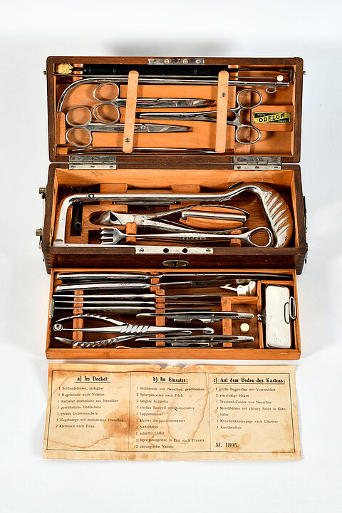 An old doctor's case with various metal cutlery and instruments for a surgeon.