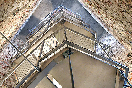 
Photo of a concrete and metal staircase in a narrow tower